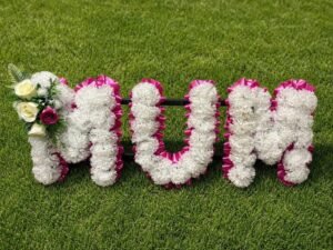Floral "MUM" tribute on green grass.